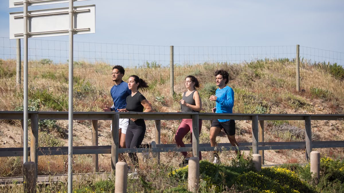 Four adults jogging on a boardwalk in Portugal, promoting a healthy lifestyle.